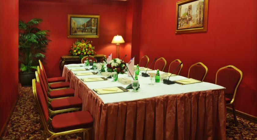 マカレム アイヤッド メッカ ホテル エクステリア 写真 The photo shows a conference or meeting room with a long table set up for discussions or presentations. The table is covered with a white tablecloth and has several place settings, including notepads and pens. There are green bottles of water on the 