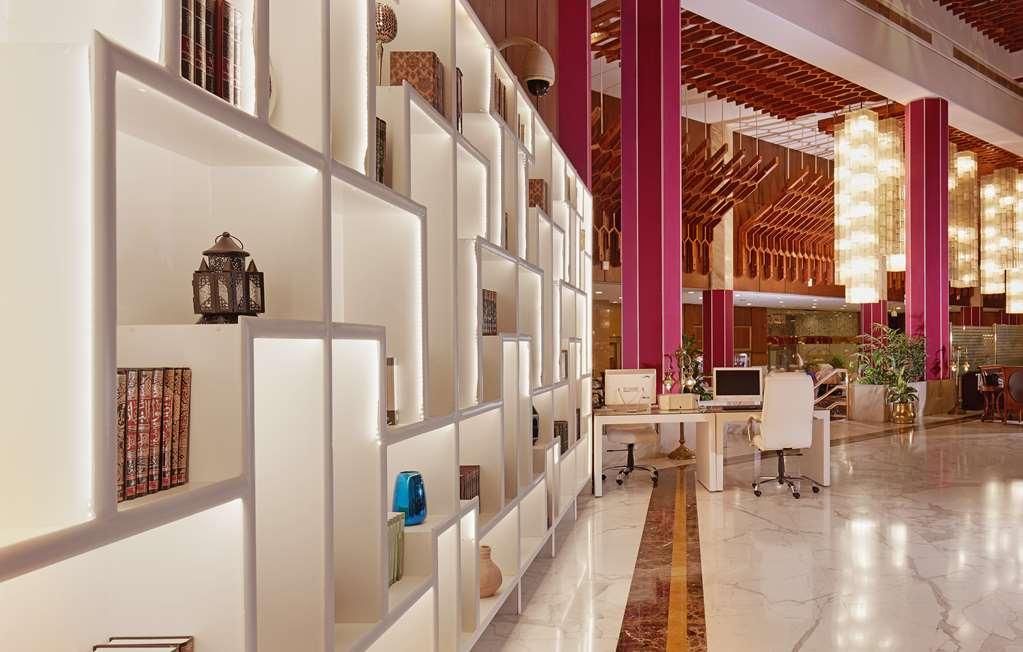 マカレム アイヤッド メッカ ホテル インテリア 写真 The photo shows a modern interior space, likely a lobby or lounge area of a stylish hotel or building. There is a partition wall made up of white shelving units illuminated from within, displaying various decorative items, books, and vases. The desig