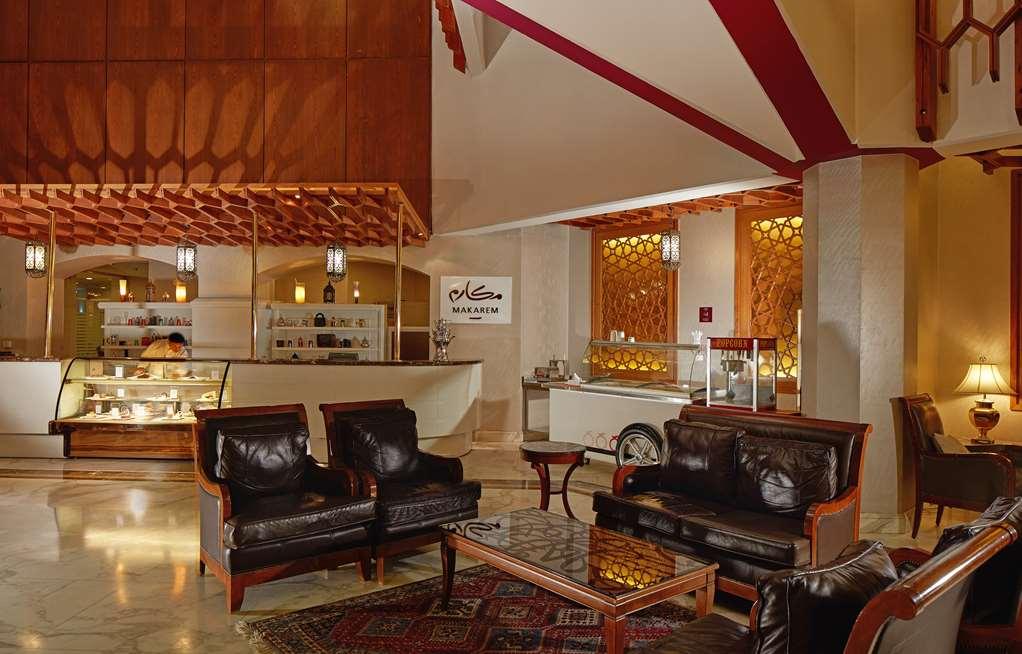 マカレム アイヤッド メッカ ホテル インテリア 写真 The photo shows a stylish interior of a lobby or lounge area. It features a seating arrangement with dark leather armchairs and a wooden table in front of them. The decor includes an intricate ceiling design and decorative wall elements that add a wa