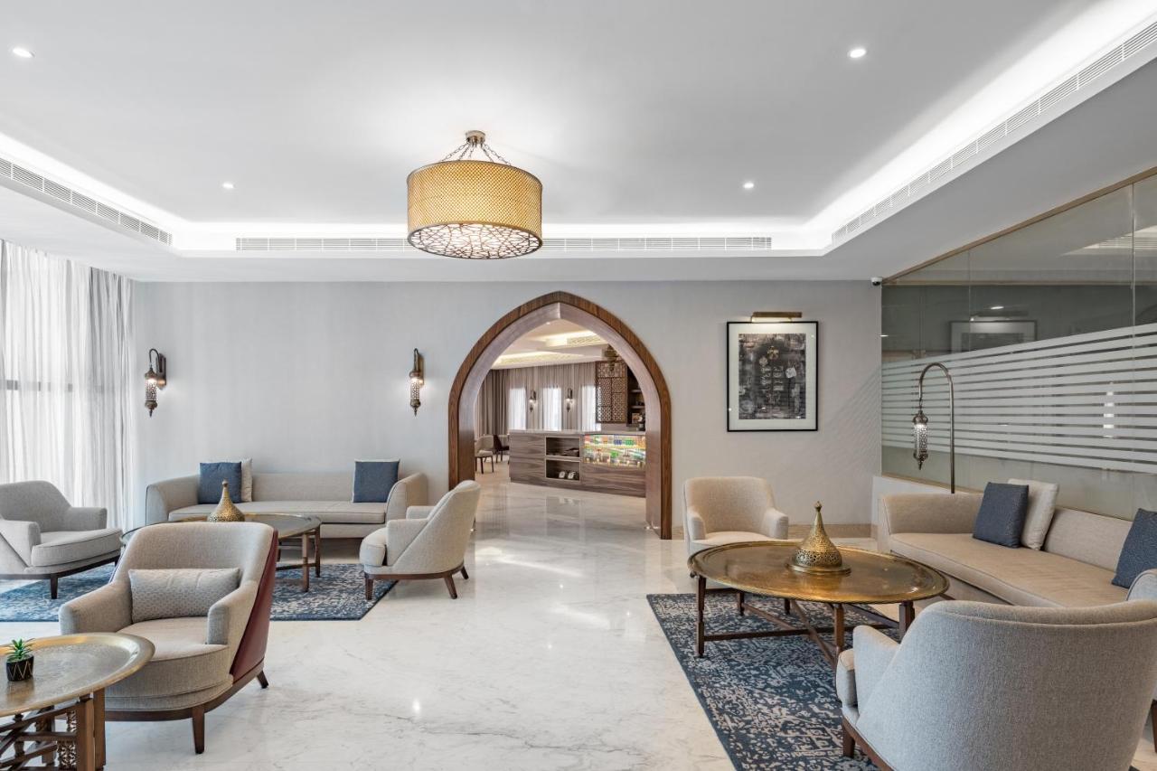 マカレム アイヤッド メッカ ホテル エクステリア 写真 The photo shows a modern and elegantly designed lounge area. It features light-colored walls and marble flooring, complemented by stylish furniture including several armchairs and small tables. The lighting is soft, provided by a decorative chandelie
