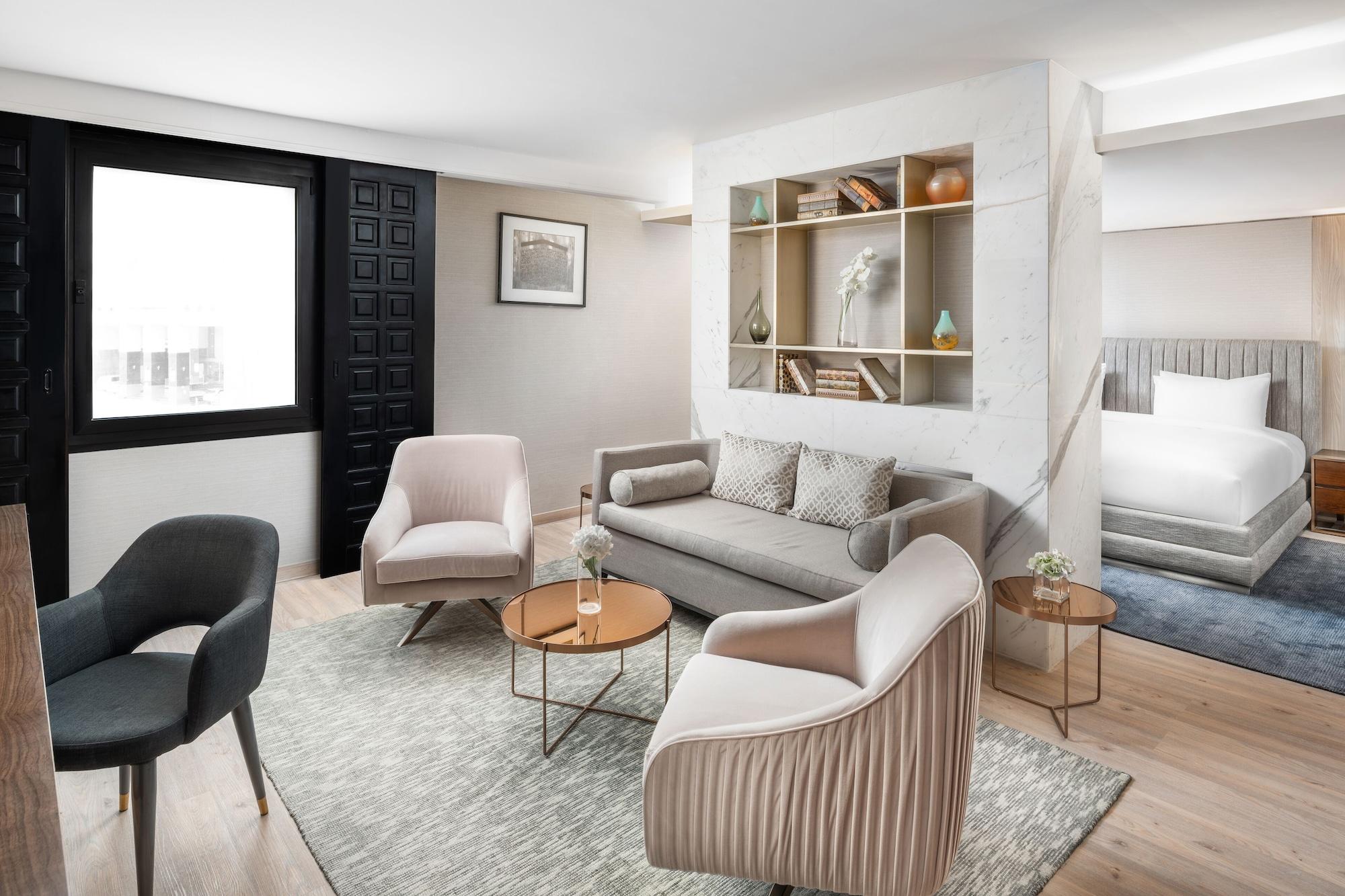 マカレム アイヤッド メッカ ホテル エクステリア 写真 The photo shows a stylish and modern living space. There is a comfortable sofa in a neutral color, accompanied by two elegant armchairs and a small round table. The floor is wooden, adding warmth to the room. A decorative shelf in the background feat