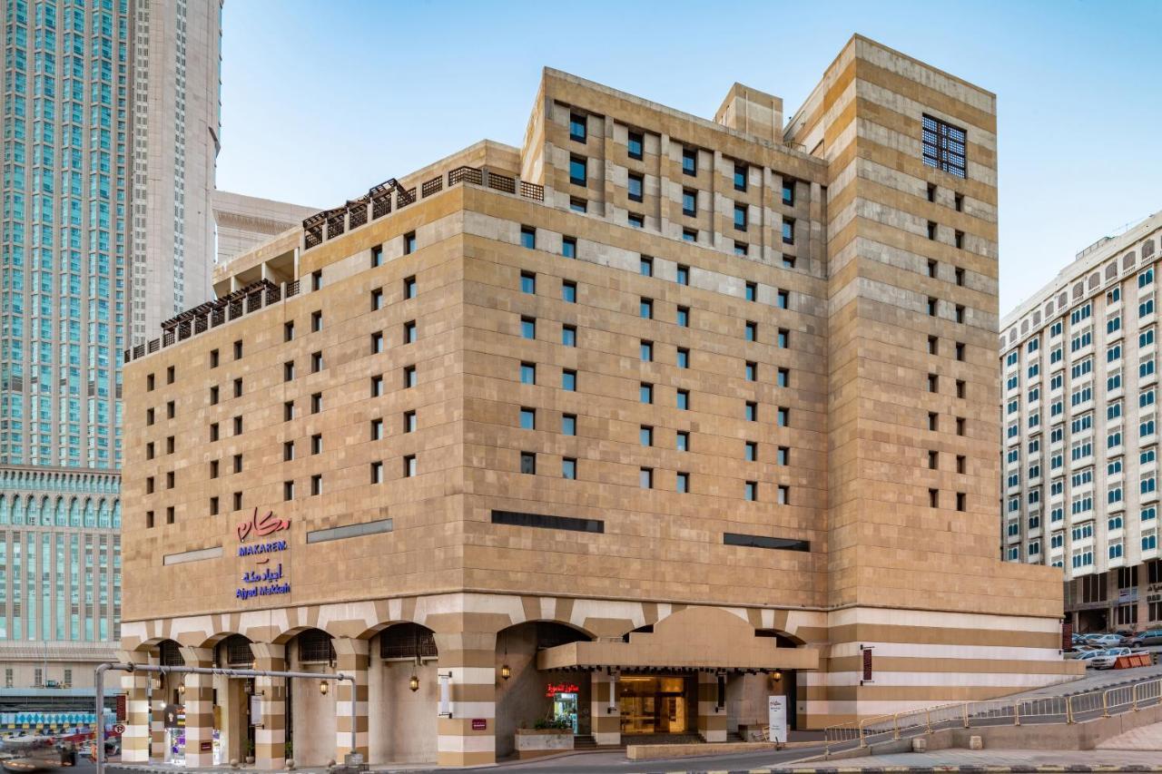 マカレム アイヤッド メッカ ホテル エクステリア 写真 The photo shows a multi-story building with a distinctive architectural style. The facade features a combination of textured stone and concrete, giving it a contemporary yet somewhat traditional appearance. The building has multiple windows arranged 