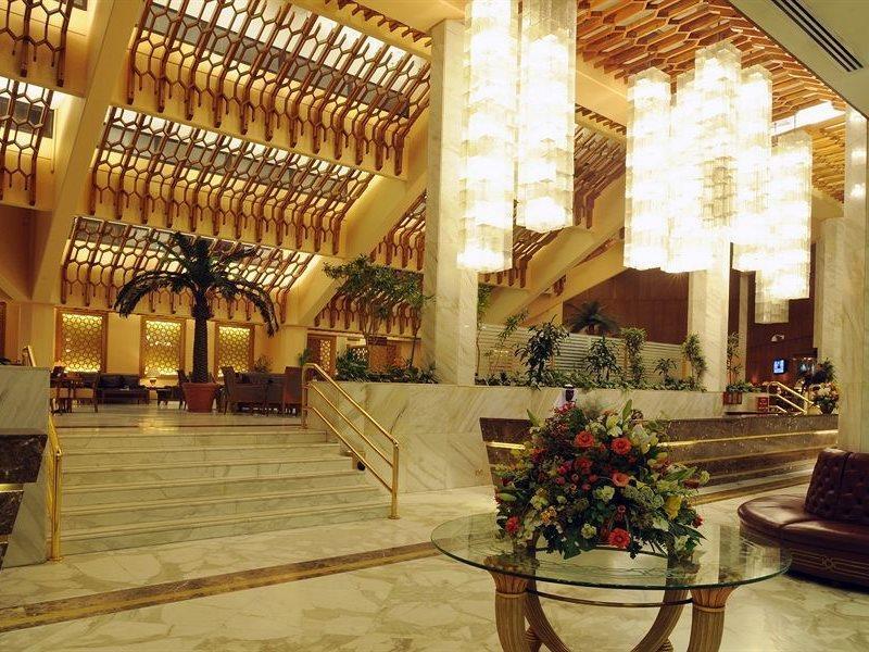 マカレム アイヤッド メッカ ホテル エクステリア 写真 The photo shows a luxurious hotel lobby with elegant design features. It has high ceilings adorned with wooden beams and large, decorative light fixtures hanging from above. The lobby is brightly lit, creating a warm and inviting atmosphere. There ar