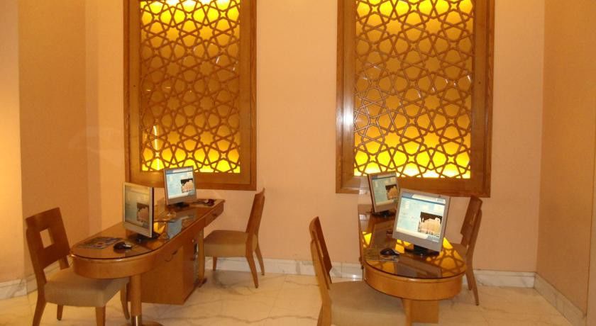 マカレム アイヤッド メッカ ホテル エクステリア 写真 The image shows a room with a warm, inviting atmosphere, featuring two wooden desks equipped with computers. Each desk has a chair positioned in front of it. The walls are adorned with decorative panels that exhibit intricate patterns, illuminated by