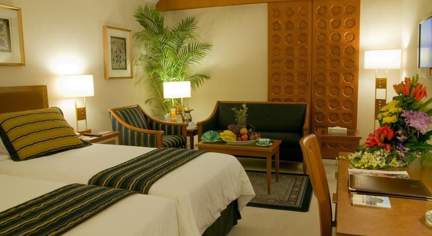 マカレム アイヤッド メッカ ホテル エクステリア 写真 The photo shows a cozy hotel room that features two single beds with white linens and dark green and striped blankets. There is a decorative rug on the floor. Against one wall, there is a large wooden partition with a distinctive geometric pattern. T