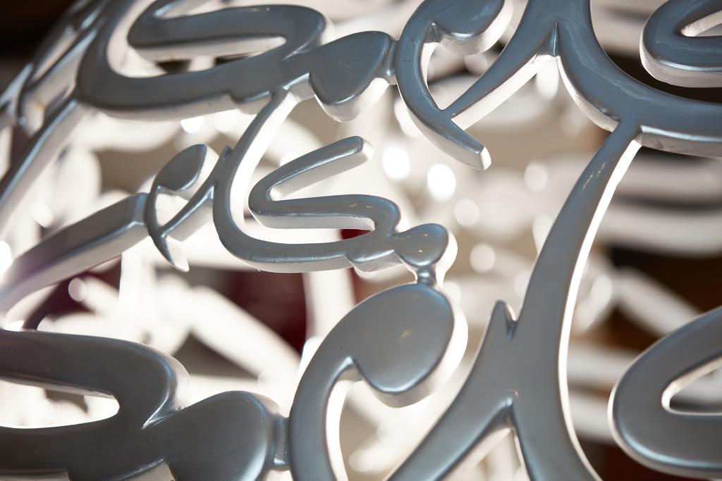 マカレム アイヤッド メッカ ホテル エクステリア 写真 The photo shows a close-up of a white, artistic structure or piece of decor that features intricate, stylized lettering. The letters are intertwined and have a fluid, modern design. The focus on the details reveals the elegance of the curves and shap